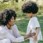 Happy mother and daughter bonding outdoors in matching outfits, showcasing love and style in a serene park.