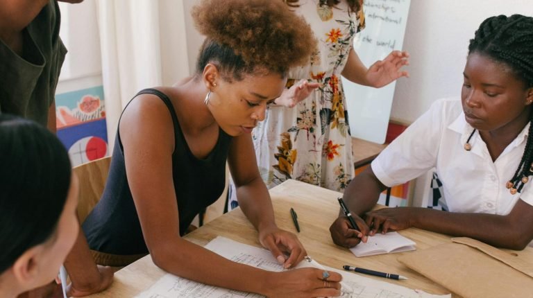 Group of women collaborating on a creative project in a modern office environment.